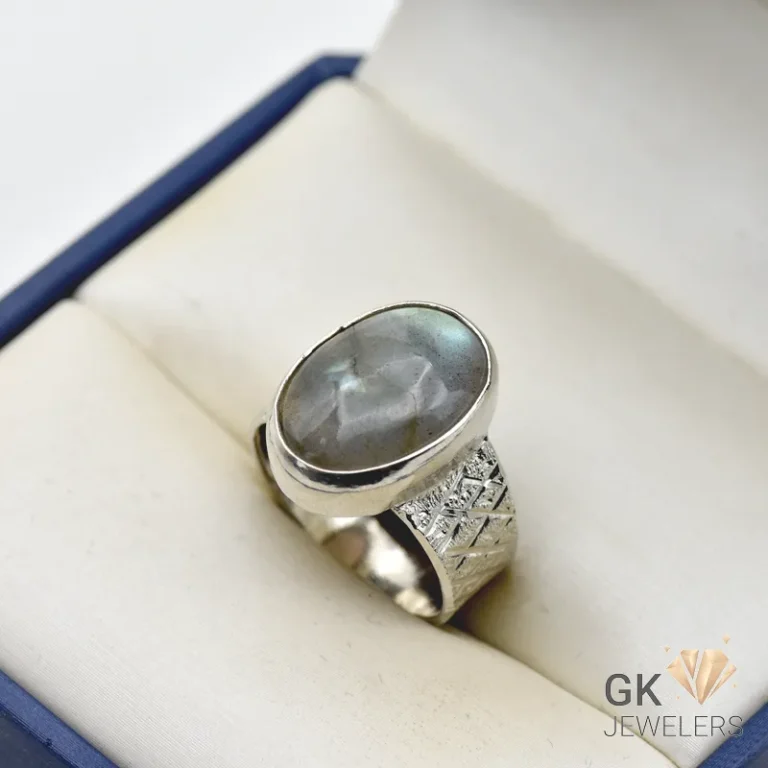 Oval Labradorite gemstone set in handmade silver ring with decorative band, displayed in a jewelry box