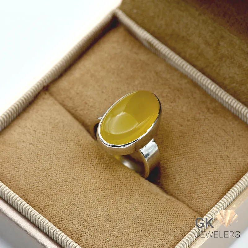 Oval yellow Agate gemstone set in handmade sterling silver ring, displayed on tan fabric in jewelry box