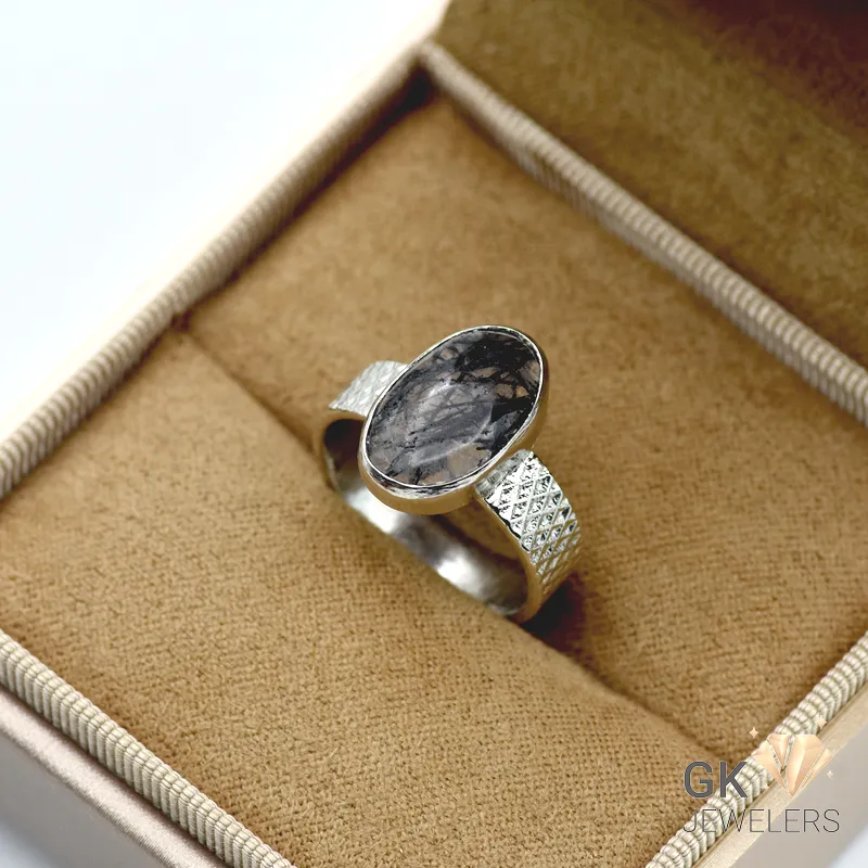Oval white quartz gemstone set in handmade 925 silver ring, displayed in a jewelry box with beige fabric