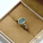 Silver ring featuring an oval-cut emerald gemstone from Zambia, displayed in a jewelry box