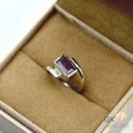 Purplish red emerald-cut ruby gemstone set in handmade 925 silver ring with translucent clarity, displayed in a jewelry box