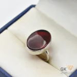 Oval maroon Yamani Agate gemstone set in a handmade silver ring, displayed in a jewelry box