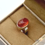 Red oval agate gemstone set in handmade 925 silver ring on beige jewelry box fabric