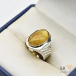 Oval-shaped natural amber gemstone set in a handmade silver ring, displayed on a cream-colored jewelry box insert