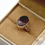 Dark brown oval agate gemstone set in handmade 925 silver ring displayed on beige jewelry box fabric