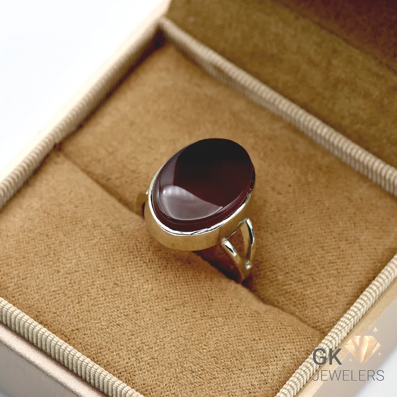 Dark brown oval agate gemstone set in handmade 925 silver ring displayed on beige jewelry box fabric