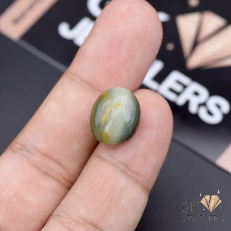 Hand holding a 10.30ct green catseye gemstone from Africa, showcasing its opaque structure and silky band