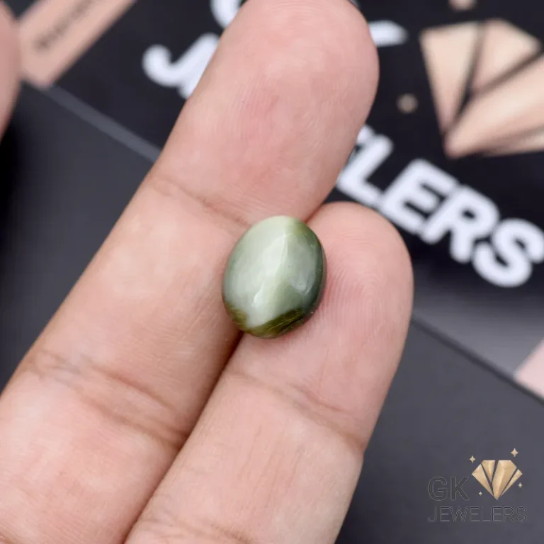 Hand holding an 8.10ct opaque green catseye gemstone from Africa, showcasing its chatoyant effect