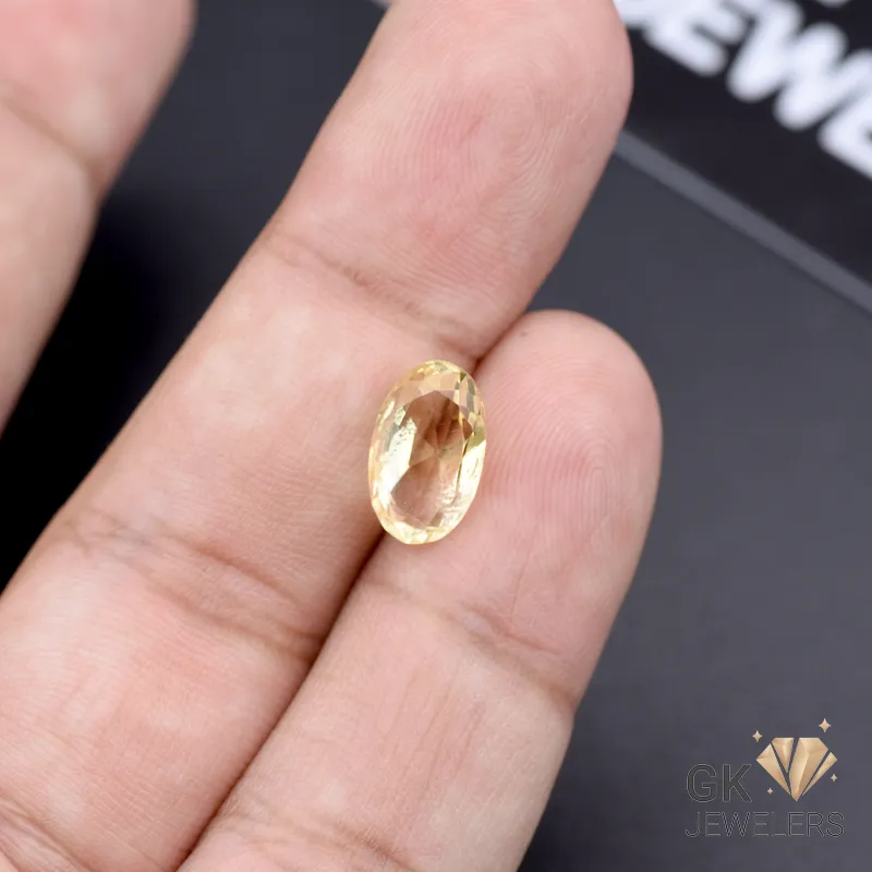Oval-cut 2.95-carat African citrine gemstone held between fingers, showcasing transparent yellow clarity
