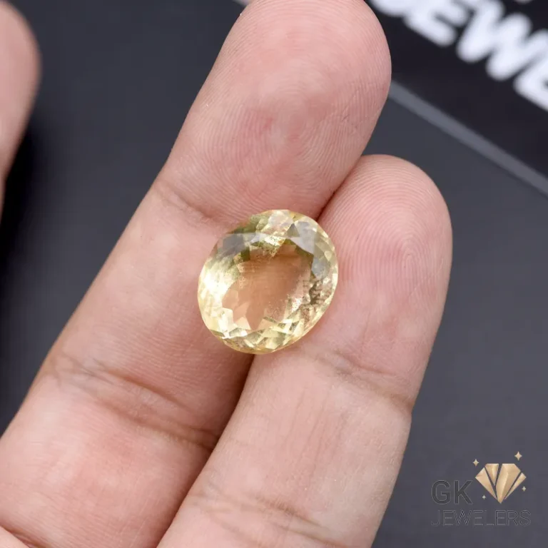 Oval-cut citrine gemstone weighing 11.65 carats held between fingers, showcasing transparent yellow color