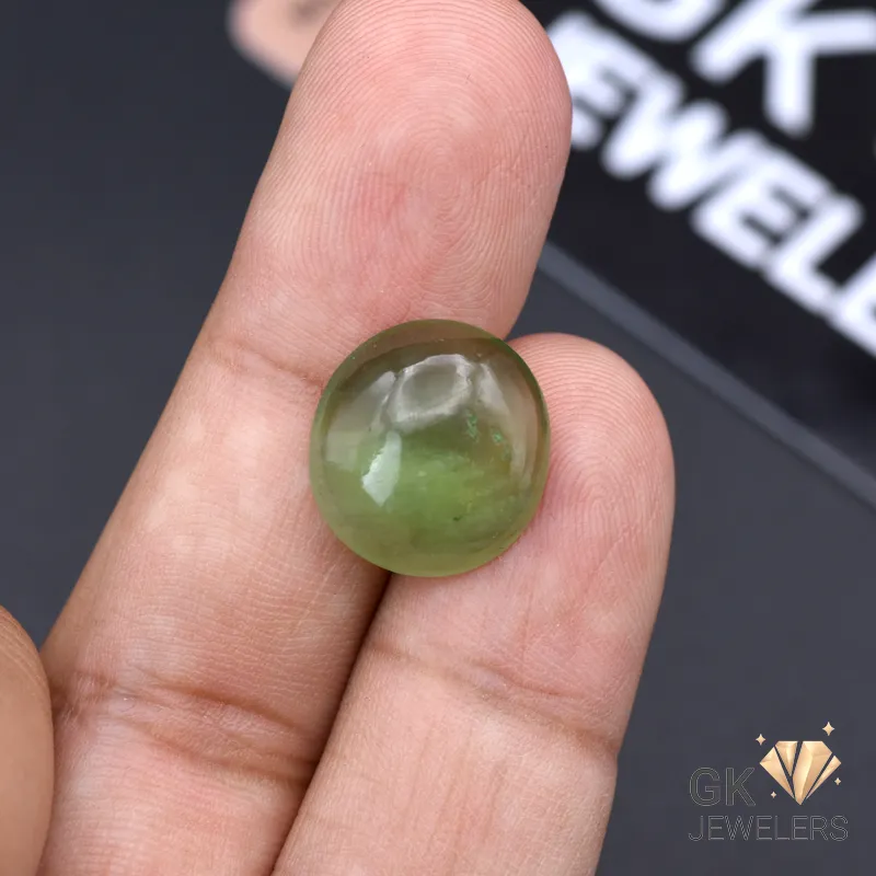 Round-cut semi-transparent green jade gemstone held between fingers
