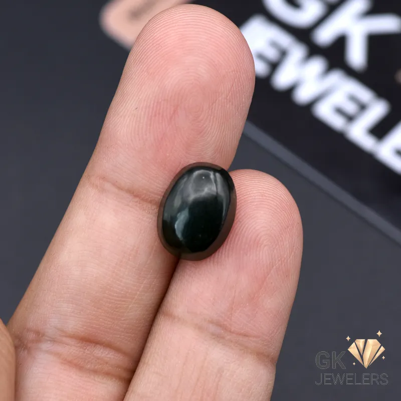 Dark green natural jade stone held between fingers, showcasing its translucent properties and round cut