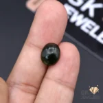 Hand holding a round, dark green translucent jade gemstone with subtle inclusions, weighing 5.50 carats from Russia