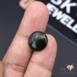 Dark green translucent jade gemstone, round cut, held between fingers, showcasing natural beauty and Russian origin