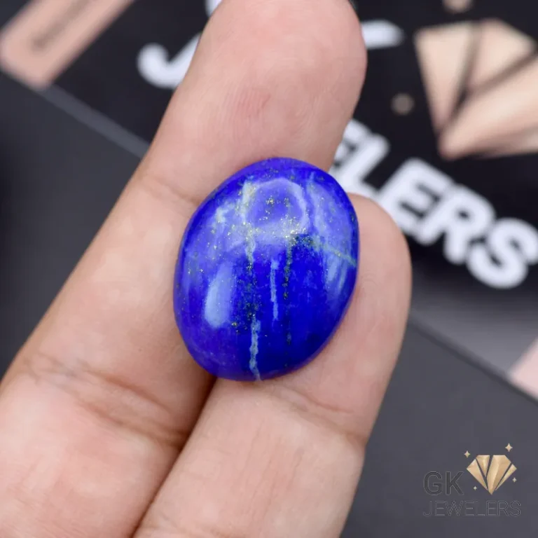 Hand holding a 21.05-carat oval-cut natural Lapis Lazuli gemstone with deep blue color and white speckles