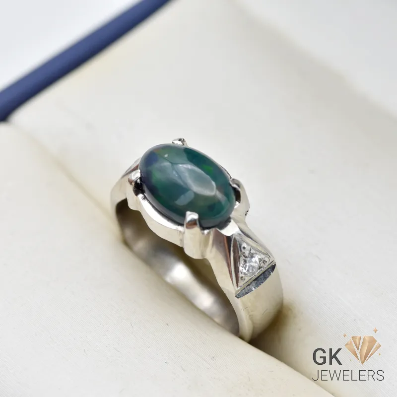 Silver ring featuring an oval-cut green Ethiopian opal gemstone with a triangular diamond accent