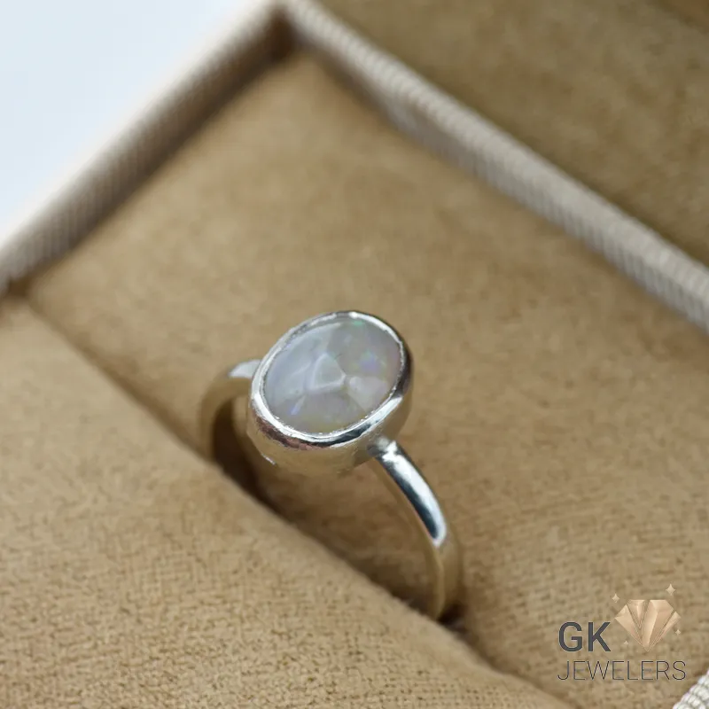 Oval Ethiopian opal gemstone set in handmade silver ring, displayed in a jewelry box with beige fabric lining