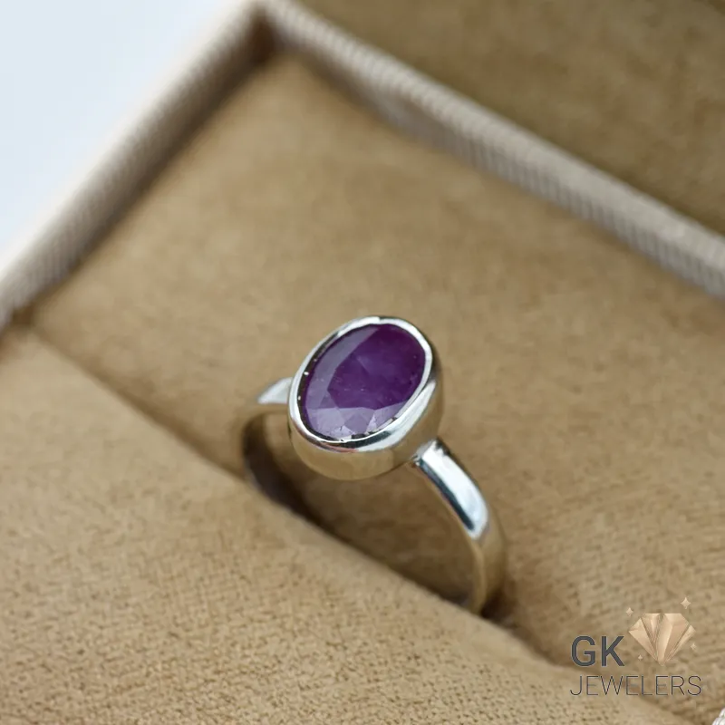 Purplish red ruby gemstone set in handmade silver ring, displayed in a jewelry box