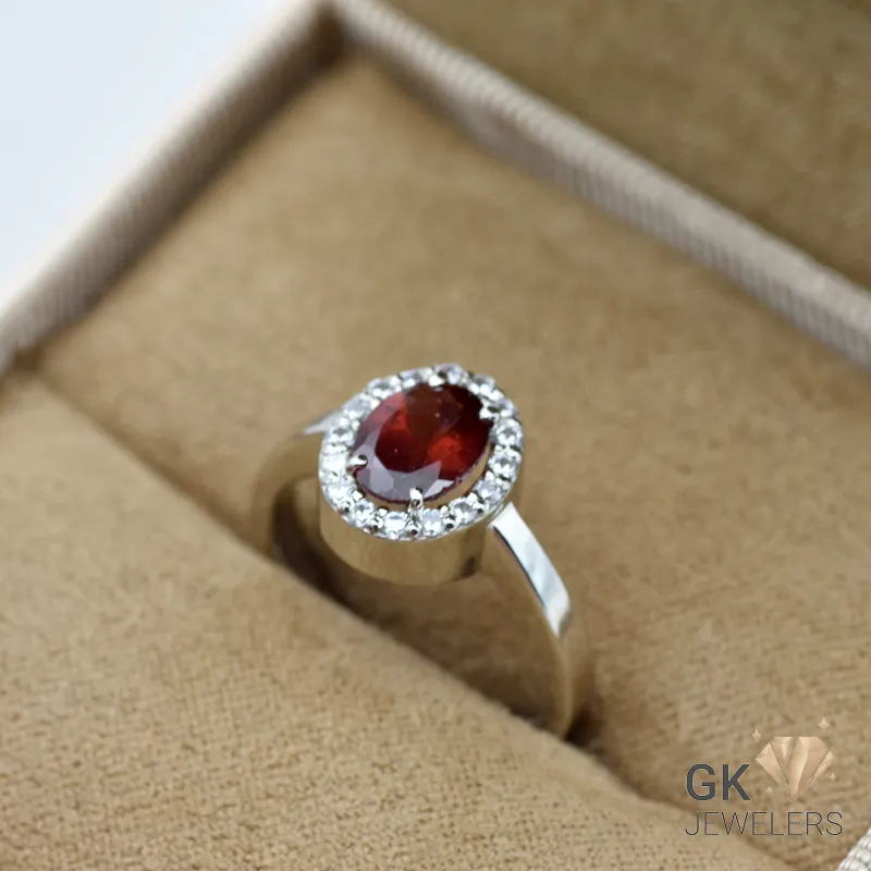 Oval-cut red garnet gemstone ring with diamond halo in silver band, handmade setting