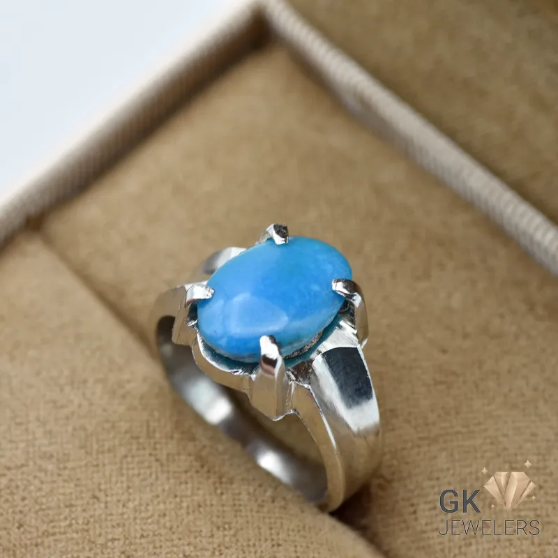 Oval blue turquoise gemstone set in a sterling silver ring with six prongs, displayed on a beige jewelry box insert
