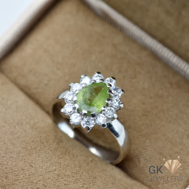 Pear-cut natural peridot gemstone surrounded by clear stones in handmade silver ring, size 16, semi-transparent green color