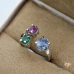 Silver ring featuring round-cut ruby, emerald, and sapphire gemstones in a handmade setting