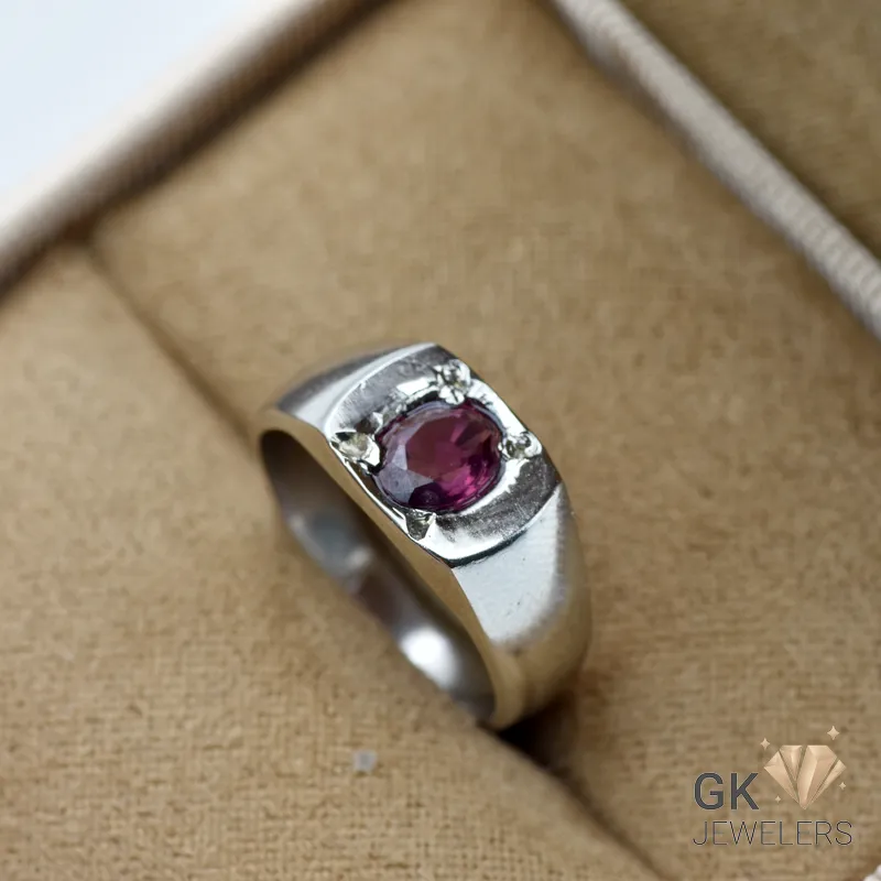 Oval purplish red garnet gemstone set in handmade silver ring on beige jewelry box fabric