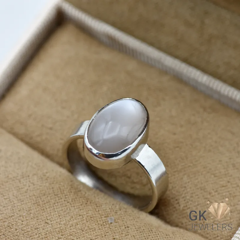 Oval gray moonstone set in sterling silver ring, displayed in beige jewelry box with textured interior