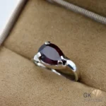 Pear-cut garnet gemstone set in handmade silver ring, purplish-red hue, transparent stone, size 15