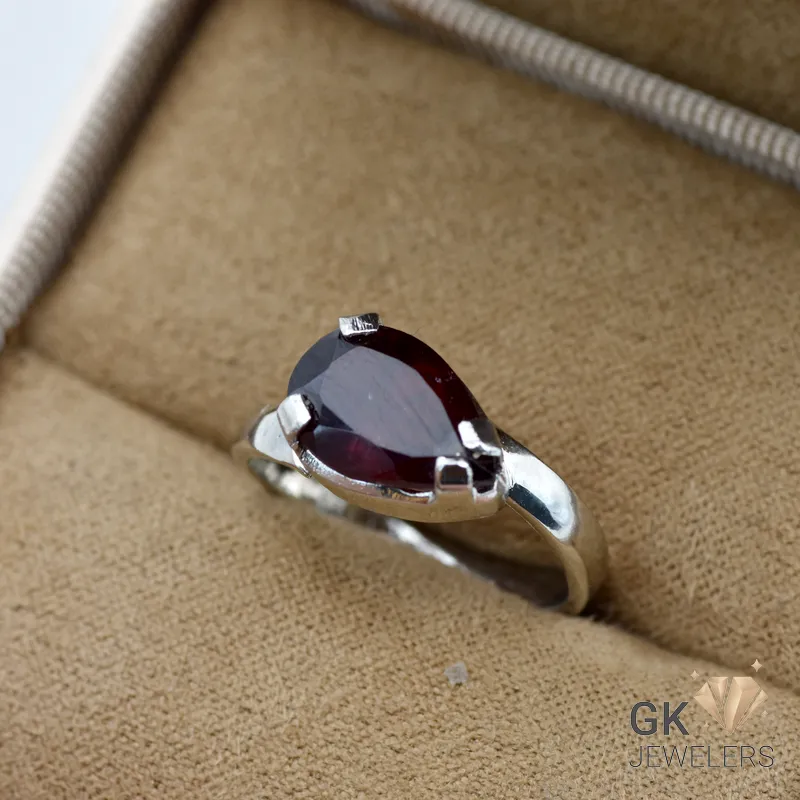 Pear-cut garnet gemstone set in handmade silver ring, purplish-red hue, transparent stone, size 15