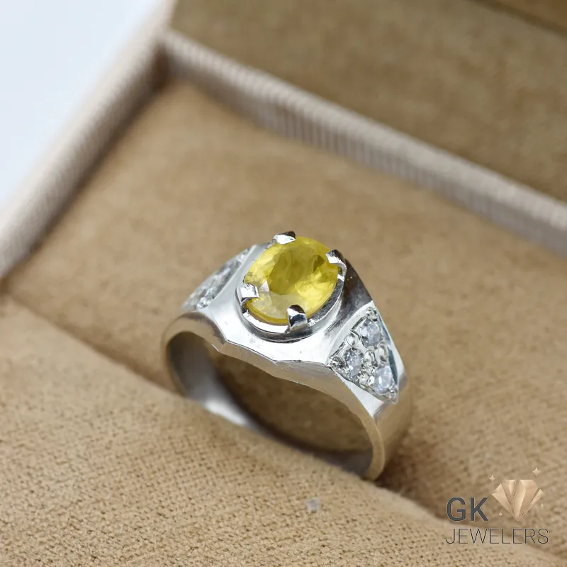 Marquise-cut yellow sapphire gemstone in a handmade silver ring with diamond accents, set on a beige fabric display