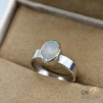 Silver ring featuring an oval Ethiopian opal gemstone with semi-transparent green hues, handmade setting, size 16