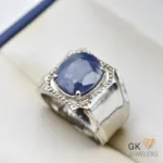 Silver ring featuring a large, deep blue, emerald-cut sapphire from Sri Lanka, set in a handmade setting with intricate details