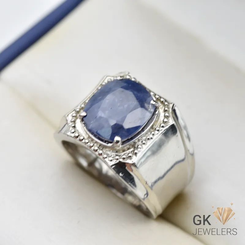 Silver ring featuring a large, deep blue, emerald-cut sapphire from Sri Lanka, set in a handmade setting with intricate details