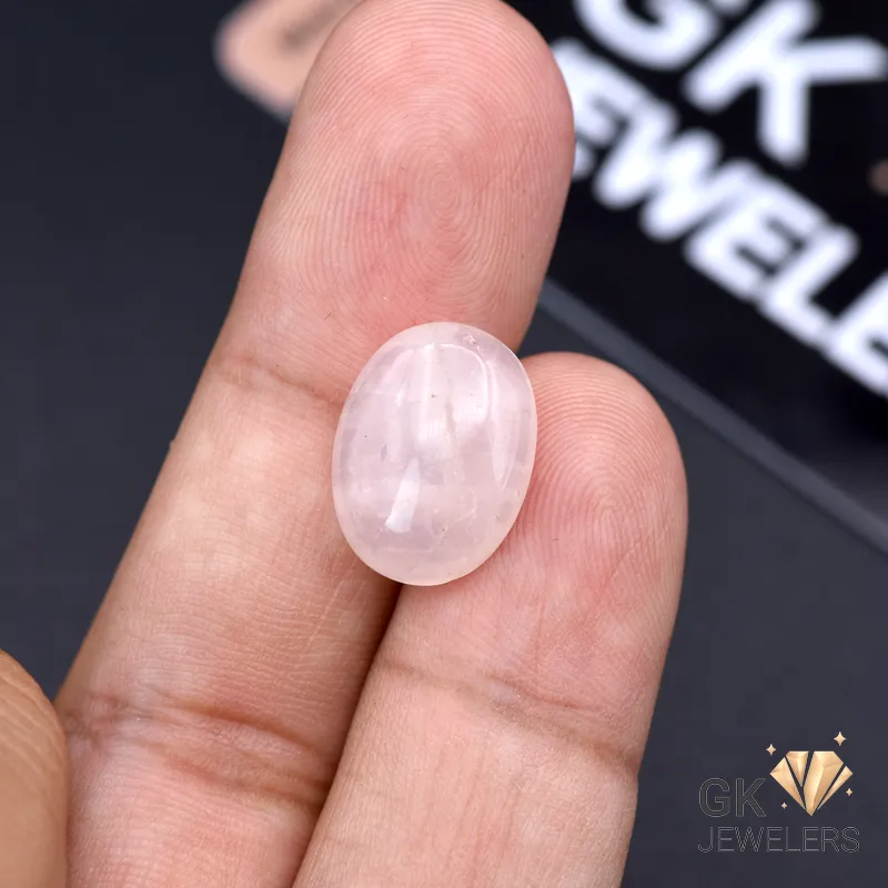 Hand holding 9.00ct oval rose quartz gemstone with pink translucent color