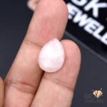Pear-shaped rose quartz gemstone held between fingers, showcasing translucent pink color and 8.70-carat weight