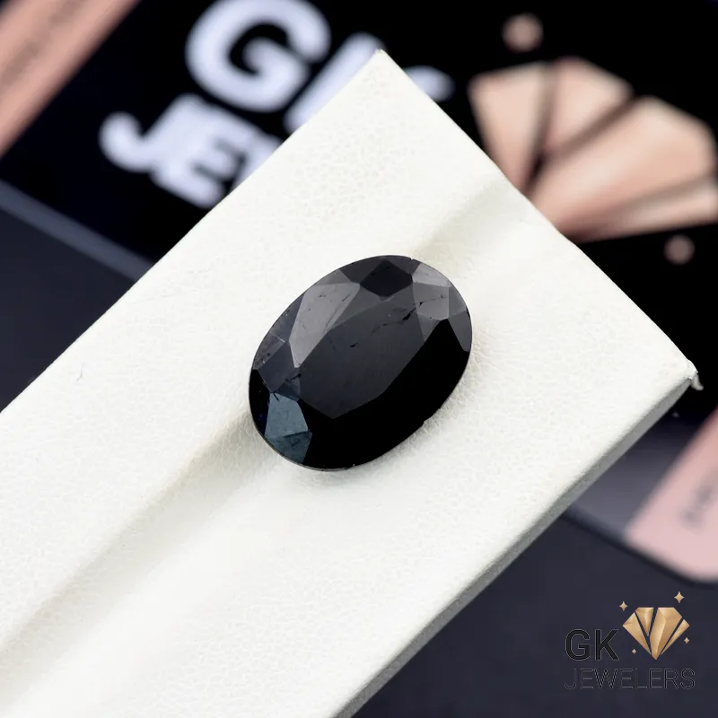 Oval-cut black tourmaline gemstone on a white display stand, showcasing its deep color and faceted surface
