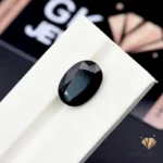 Oval-cut 9.95ct black tourmaline gemstone from Afghanistan on a white display stand