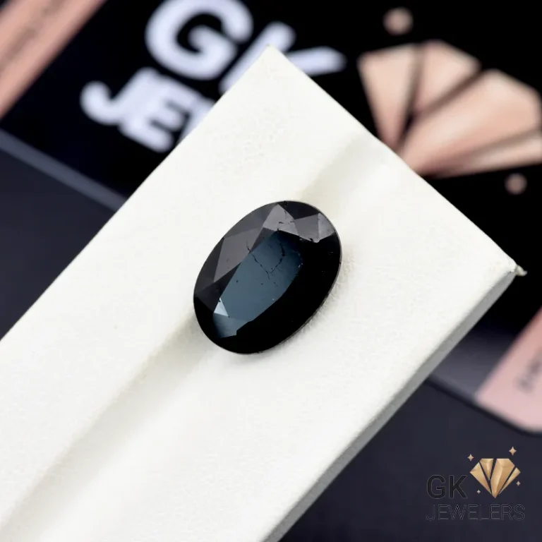 Oval-cut 9.95ct black tourmaline gemstone from Afghanistan on a white display stand