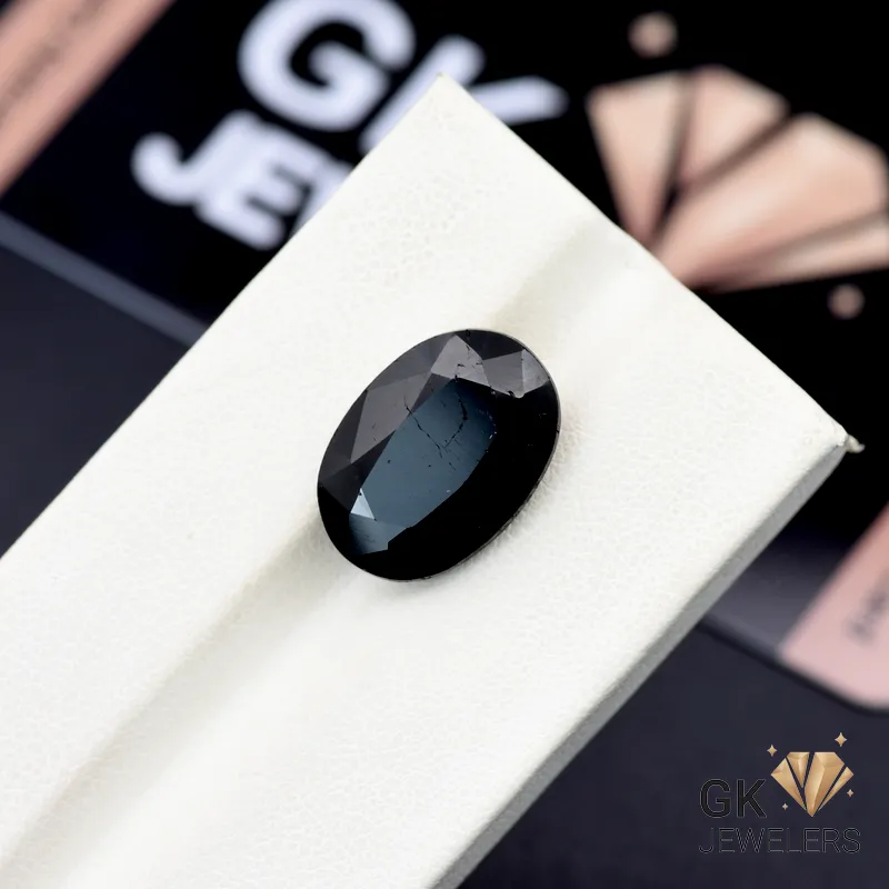 Oval-cut 9.95ct black tourmaline gemstone from Afghanistan on a white display stand