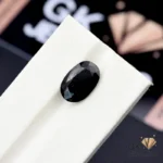 Oval-cut black tourmaline gemstone on white display stand, 5.55 carats, opaque clarity, from Afghanistan mines