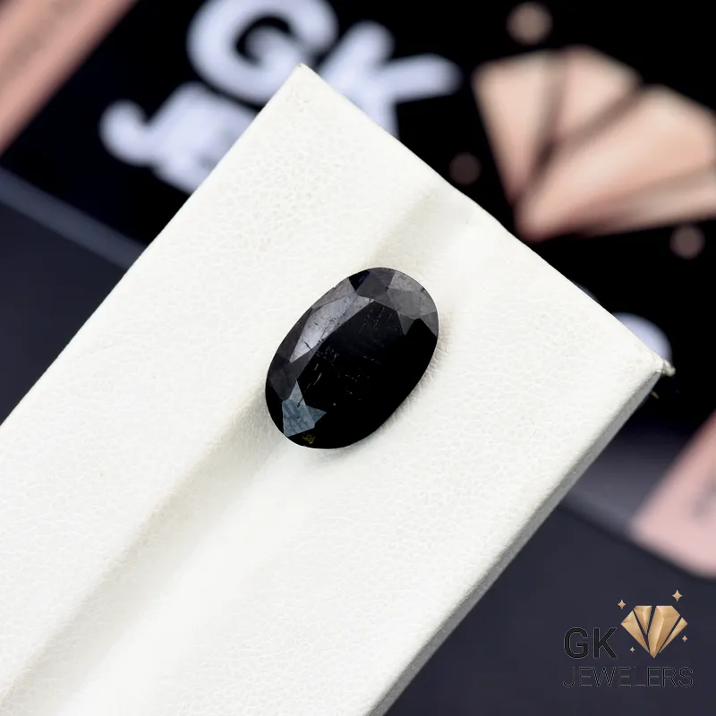 Oval-cut black tourmaline gemstone on white display stand, 5.55 carats, opaque clarity, from Afghanistan mines