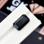 Emerald-cut black tourmaline gemstone on a white display stand
