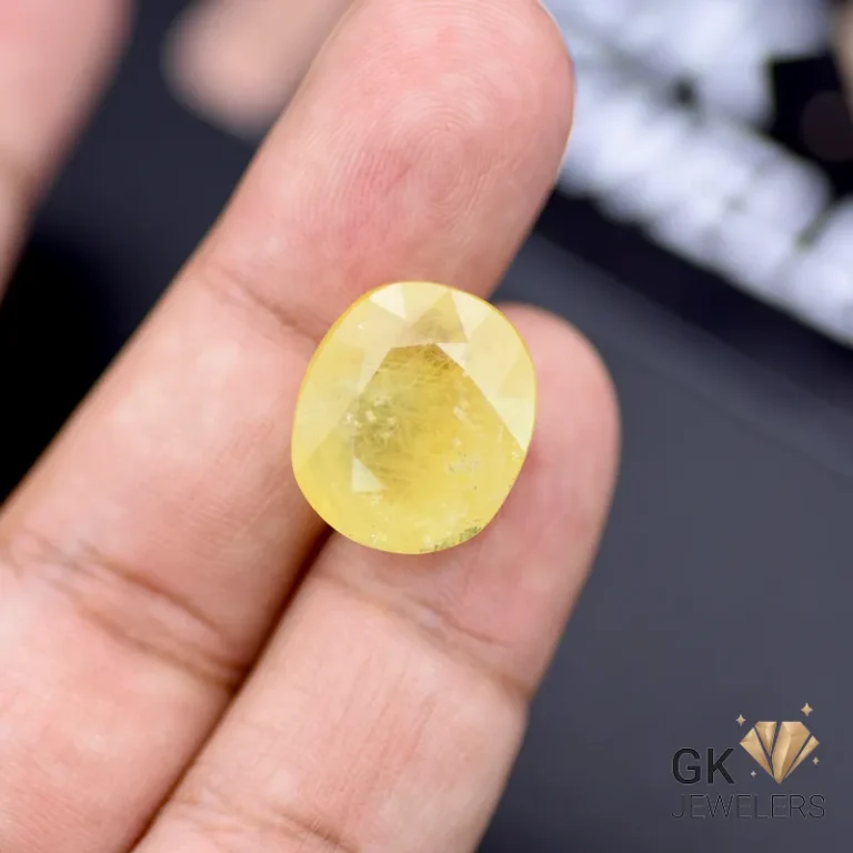 Hand holding 19.99-carat oval yellow sapphire gemstone with semi-transparent clarity