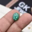 Oval green malachite gemstone held between person's index and middle fingers