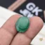 Oval green malachite gemstone held between person's thumb and finger