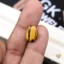 Oval tiger eye gemstone held between person's thumb and fingers