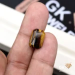 Tiger Eye gemstone held between person's thumb and index finger